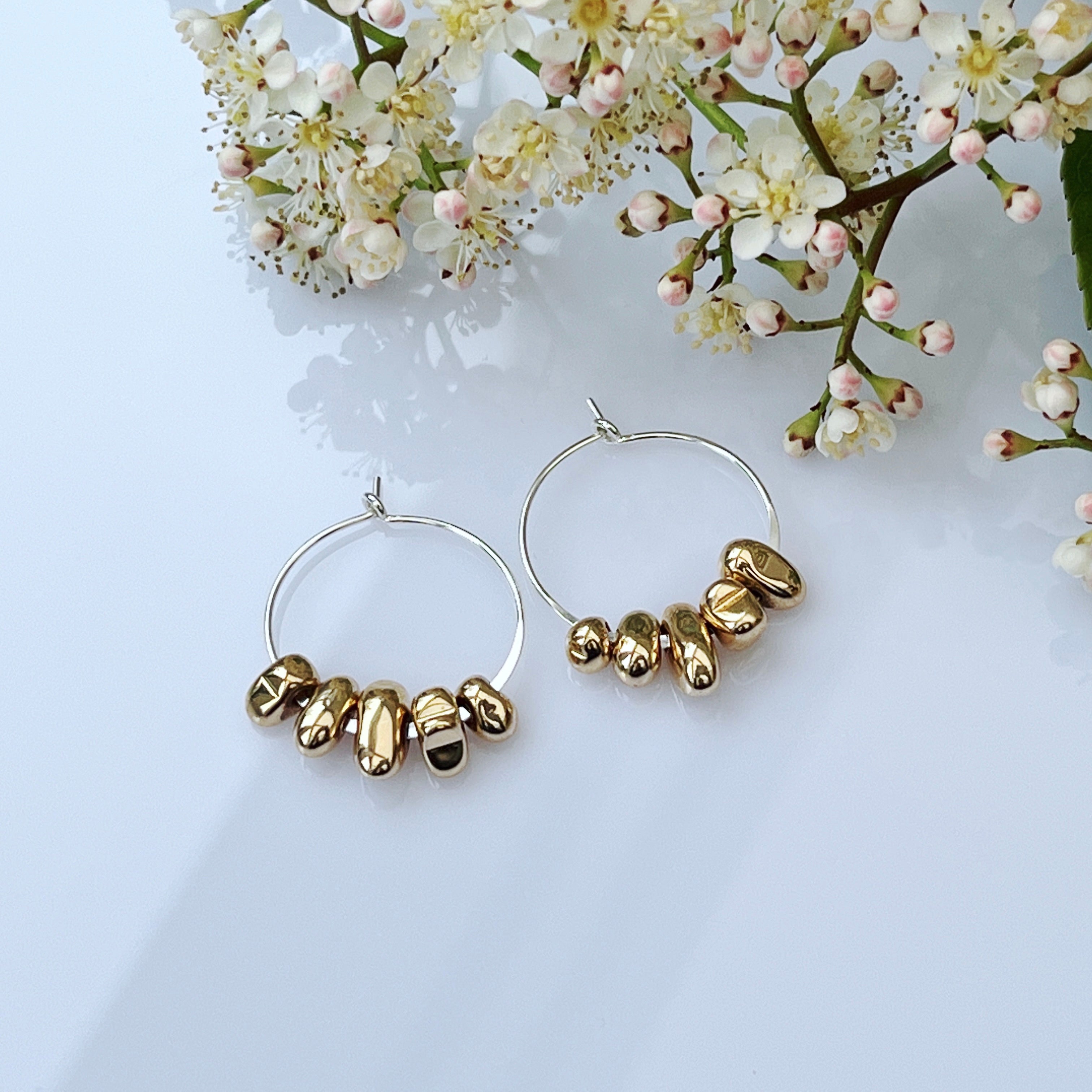 sterling silver hoop anxiety earrings with gold hematite charms flatlay